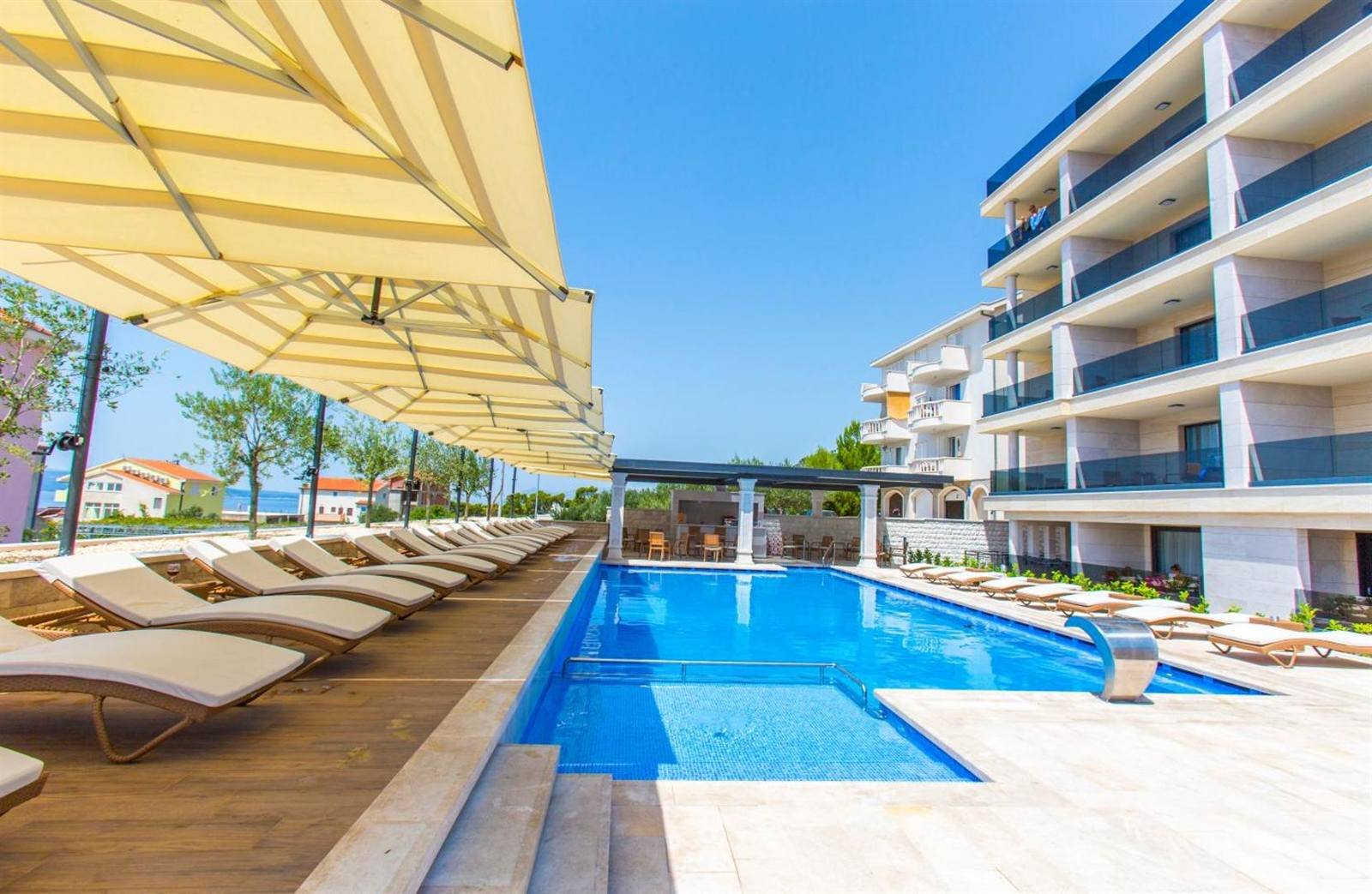 Luxury Aparthotel: pool, sun loungers and umbrellas next to the apartment building