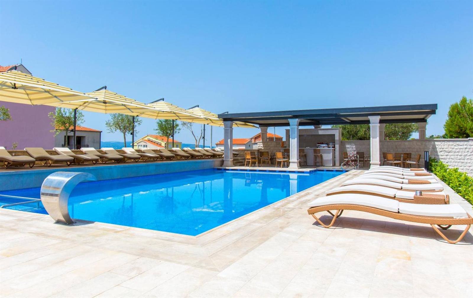 Luxury Aparthotel: swimming pool with a water feature and stone-paved terrace