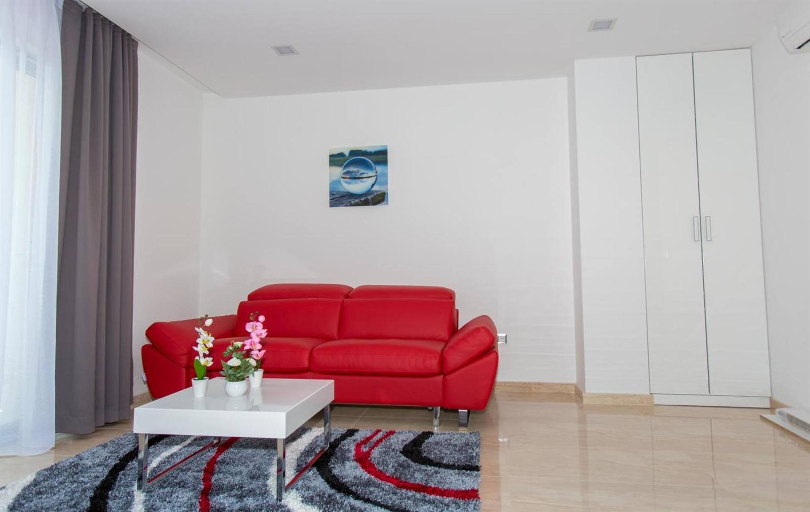 Luxury Aparthotel: living room with a red sofa and a flat-screen TV